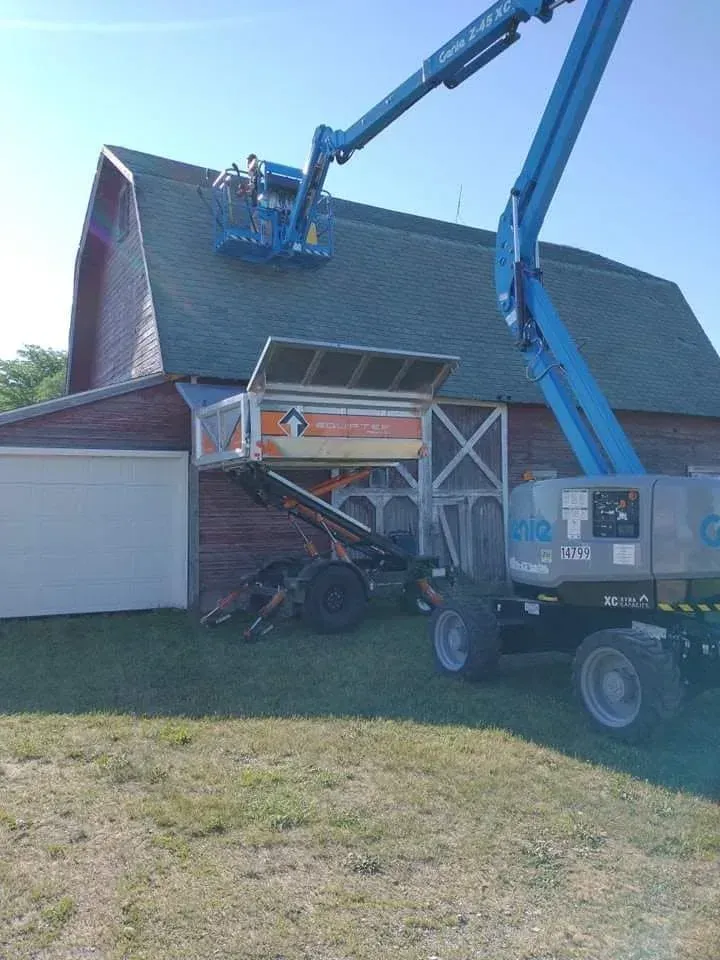 Blue boom lift removing materials from a roof of a house under renovation